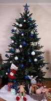 árbol de navidad con bolas de colores y cajas de regalo sobre una pared de ladrillo blanco con bolas azules y blancas foto