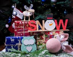 The inscription snow from a tree on a New Year's. On the spruce branches against the background of a snow cover are New Year's blue, white balls with spruce cones and a box with a gift. Christmas photo