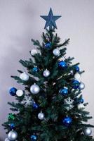 christmas tree with colorful balls and gift boxes over white brick wall with blue and white balls photo