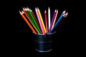 multi-colored pencils in a wine glass and a bucket. Selective blurred a group of coloring pencils in a wine glass on the isolated white or black background , Modern art. Modern photo