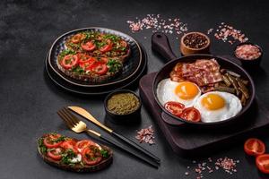Tasty breakfast consists of eggs, bacon, beans, tomatoes, with spices and herbs photo