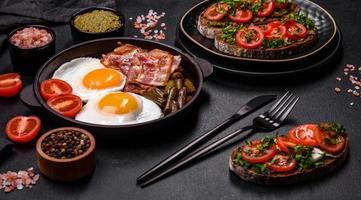 Tasty breakfast consists of eggs, bacon, beans, tomatoes, with spices and herbs photo