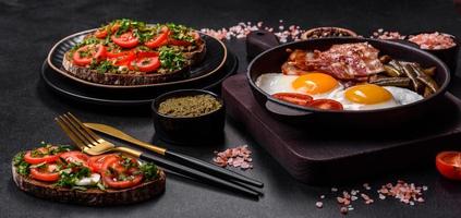 Tasty breakfast consists of eggs, bacon, beans, tomatoes, with spices and herbs photo