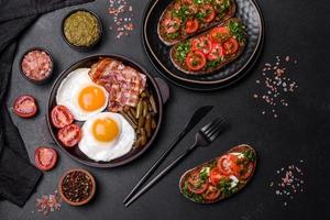 Tasty breakfast consists of eggs, bacon, beans, tomatoes, with spices and herbs photo