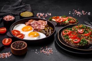 Tasty breakfast consists of eggs, bacon, beans, tomatoes, with spices and herbs photo