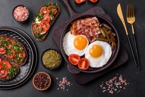 Tasty breakfast consists of eggs, bacon, beans, tomatoes, with spices and herbs photo