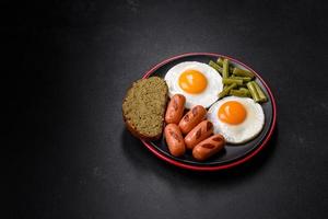 Tasty English breakfast of fried eggs, beans, asparagus, sausages with spices and herbs photo