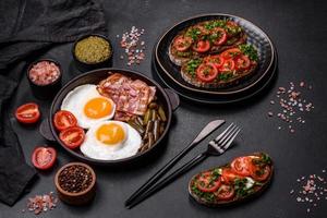 Tasty breakfast consists of eggs, bacon, beans, tomatoes, with spices and herbs photo