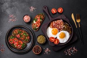 Tasty breakfast consists of eggs, bacon, beans, tomatoes, with spices and herbs photo