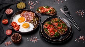 Tasty breakfast consists of eggs, bacon, beans, tomatoes, with spices and herbs photo