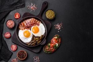 Tasty breakfast consists of eggs, bacon, beans, tomatoes, with spices and herbs photo