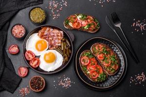Tasty breakfast consists of eggs, bacon, beans, tomatoes, with spices and herbs photo