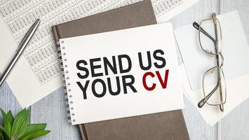 send us your cv word on brown diary and charts with pen and glasses photo