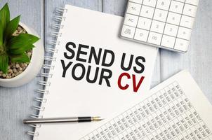 white notebook, charts, pen and send us your cv words photo