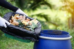 el jardinero sostiene basura orgánica, desechos de cocina podridos con frutas y desechos de basura vegetal en una bolsa de plástico negra para hacer fertilizante de compost para usar en la agricultura. concepto, gestión de residuos. foto