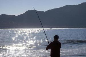 Silhouette of the fisherman at sunset photo