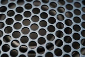 Fragment of the speaker with a metal perforated grille. Speaker texture, blue and black. Macro shot of speaker grille. Vintage effect. Close up shot of Acoustic broadband speaker. photo
