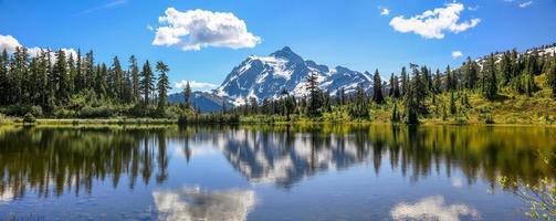 Mount Shuksan with reflections in Picture lake in Mount Baker recreation area, Evergreen trees by the lake Washington Pacific Northwest USA.