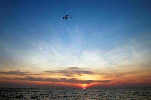 la hermosa vista del mar con un avión en el cielo durante una colorida puesta de sol. Phuket, Tailandia. foto