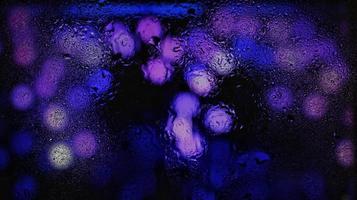 Purple Neon Blurred Lights Through Glass Window With Raindrops On It photo