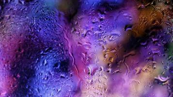 Purple Neon Blurred Lights Through Glass Window With Raindrops On It photo