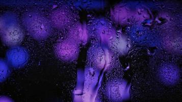Purple Neon Blurred Lights Through Glass Window With Raindrops On It photo