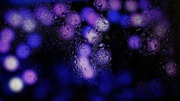 Purple Neon Blurred Lights Through Glass Window With Raindrops On It photo