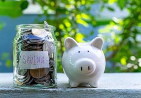 Piggy bank bottle with saving sign on natural bokeh background photo