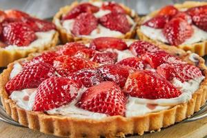 Round cream pie with strawberries. One big and three small photo