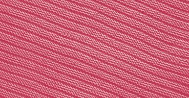 Texture of smooth knitted sweater with pattern. Handmade knitting wool or cotton fabric texture. Background of Large knit pattern with knitting needle or crochet. Color Of The Year 2023 - Viva Magenta photo