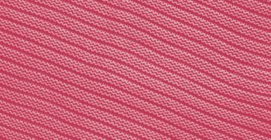 Texture of smooth knitted sweater with pattern. Handmade knitting wool or cotton fabric texture. Background of Large knit pattern with knitting needle or crochet. Color Of The Year 2023 - Viva Magenta photo