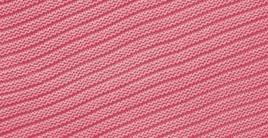 Texture of smooth knitted sweater with pattern. Handmade knitting wool or cotton fabric texture. Background of Large knit pattern with knitting needle or crochet. Color Of The Year 2023 - Viva Magenta photo