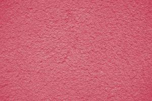 Background of peeling Magenta paint on an old wall. Texture background of an old wall made of plaster. Cracks. Copy space. Old peeling plaster wall, crumbles. Color Of The Year 2023 - Viva Magenta. photo