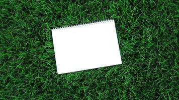 Empty white paper on green grass background. For message flat lay with copy space for text or products presentation. Nature concept, business and lifestyle environment. photo