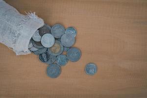 Close up of money bag pour the coin on the wooden table background, photo