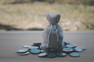 Money bag around by coin on the wooden table blur background photo