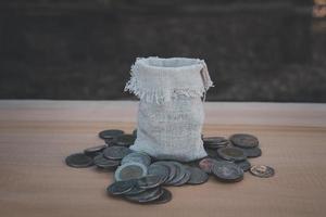 abriendo la bolsa de dinero alrededor de la moneda en la mesa de madera fondo borroso foto