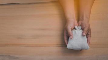 Top view of hands holding money bag on the wooden table background photo