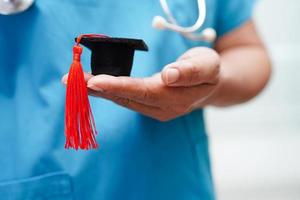 Asian woman doctor holding graduation hat in hospital, Medical education concept. photo