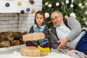 abuelo sosteniendo un regalo. abuelo y nieta navidad foto