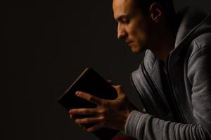 un hombre rezando sosteniendo una biblia sagrada. foto