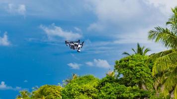 Professional drone quadcopter with digital camera on tropical beach. Taking footage of honeymoon location and tourist vacation content. Digital technology for special locations