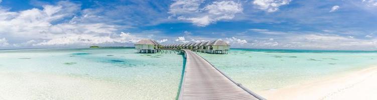 Maldives island beach panorama. Luxury water villas long wooden pier pathway. Tropical vacation and summer holiday background concept. Amazing scenery with copy space photo