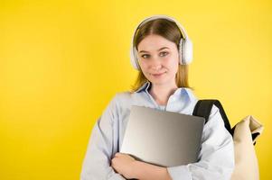 Happy caucasian girl in the headphones listens to podcast,e-book etc holding laptop. Online education.App for learning concept.Copyspace banner photo