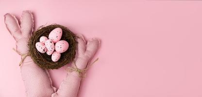 Monochrome easter banner. Pink toy bunnies near pink eggs.Banner with place for text photo