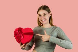 Closeup studio portrait of young female holding heart shaped gift box. St valentines day concept photo