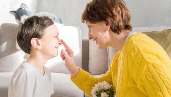 Beautiful woman touching her son's nose. Family relationship concept photo