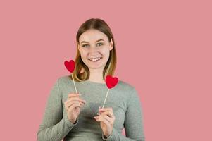 mujer rubia sonriente con corazones sobre fondo rosa. retrato de estudio de san valentín foto