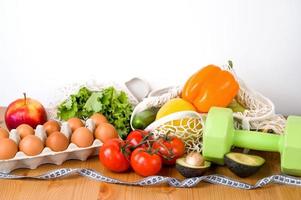 verduras y frutas cerca de pesas y cinta métrica. concepto de deporte y dieta. habitos de comer saludable foto