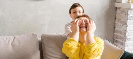 Son closing his mother eyes with his hands.Happy family.prepapring surprise photo